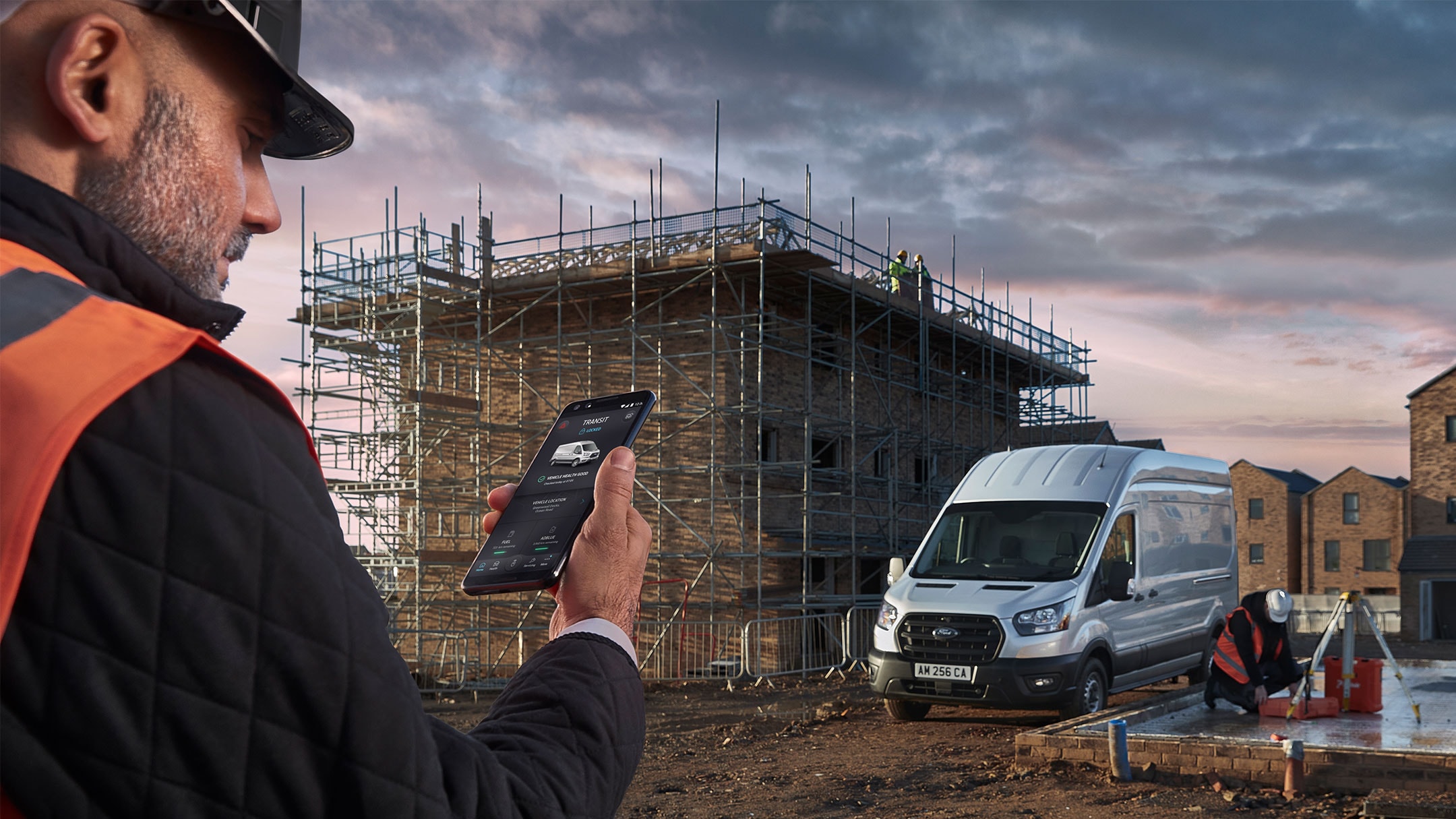 Construction worker checking phone with Ford Van at background