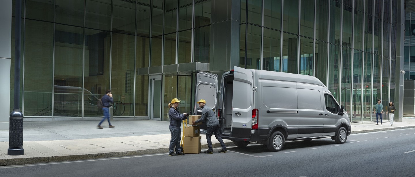 New Ford E-Transit with delivery men loading up boxes in 3/4 back view