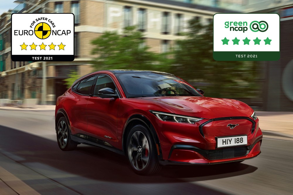 A red Mustang Mach-E driving along a road with NCAP safety award logos overlaid. 