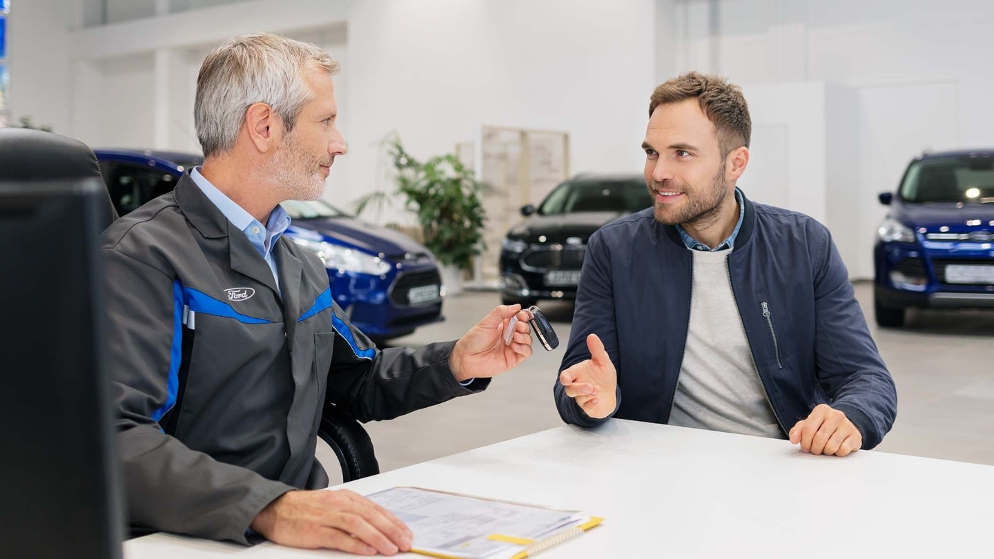 Two men sitting across from each other at a dealership