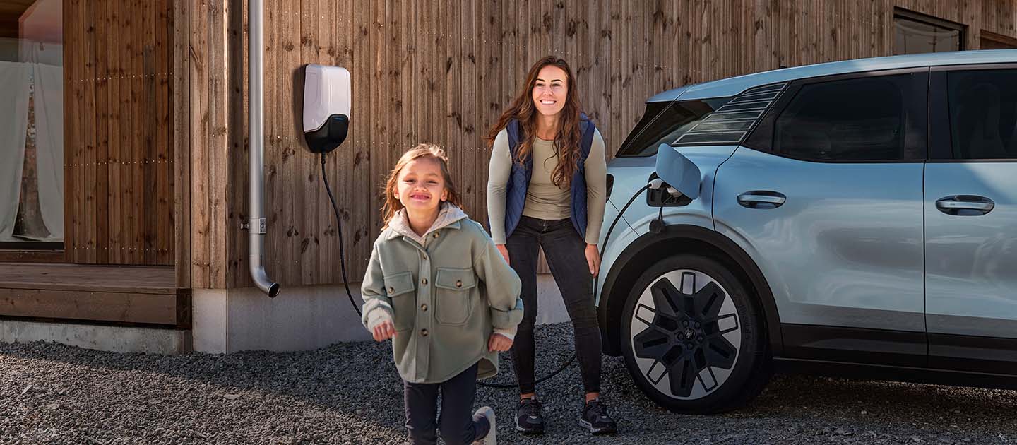 A family having fun while charging their electric Ford Explorer with an outdoor EV home charger.
