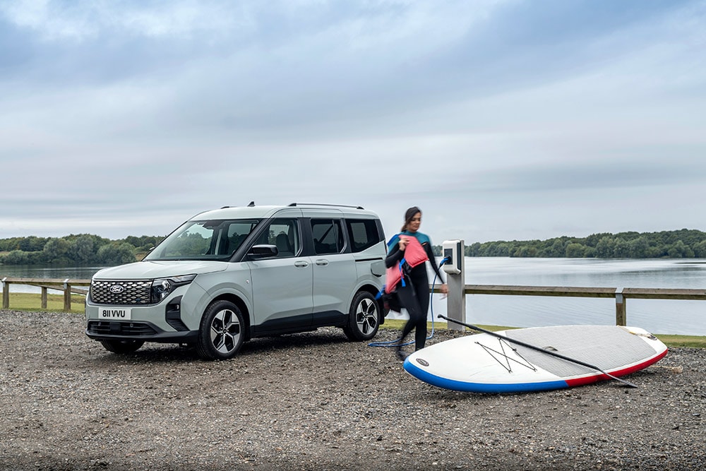 A stand-up paddle boarder unloads equipment from the new Ford E-Tourneo Courier MPV.