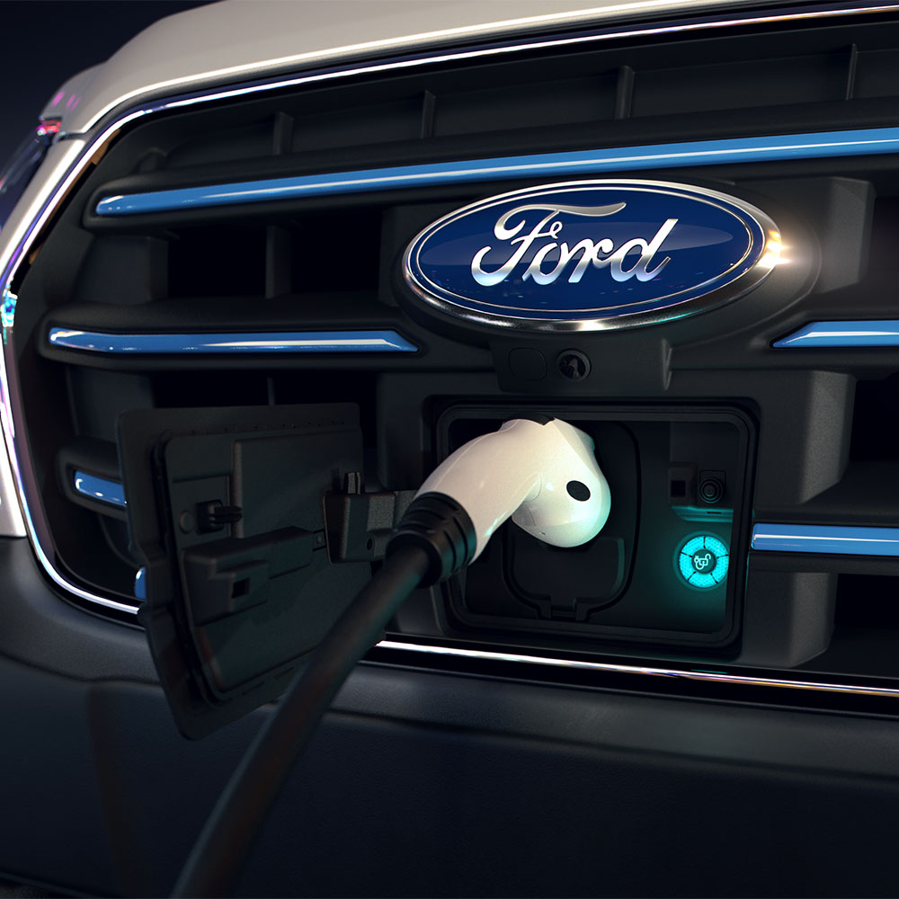 Close-up of an Ford E-Transit van charging point and blue oval Ford badge on the front grille.
