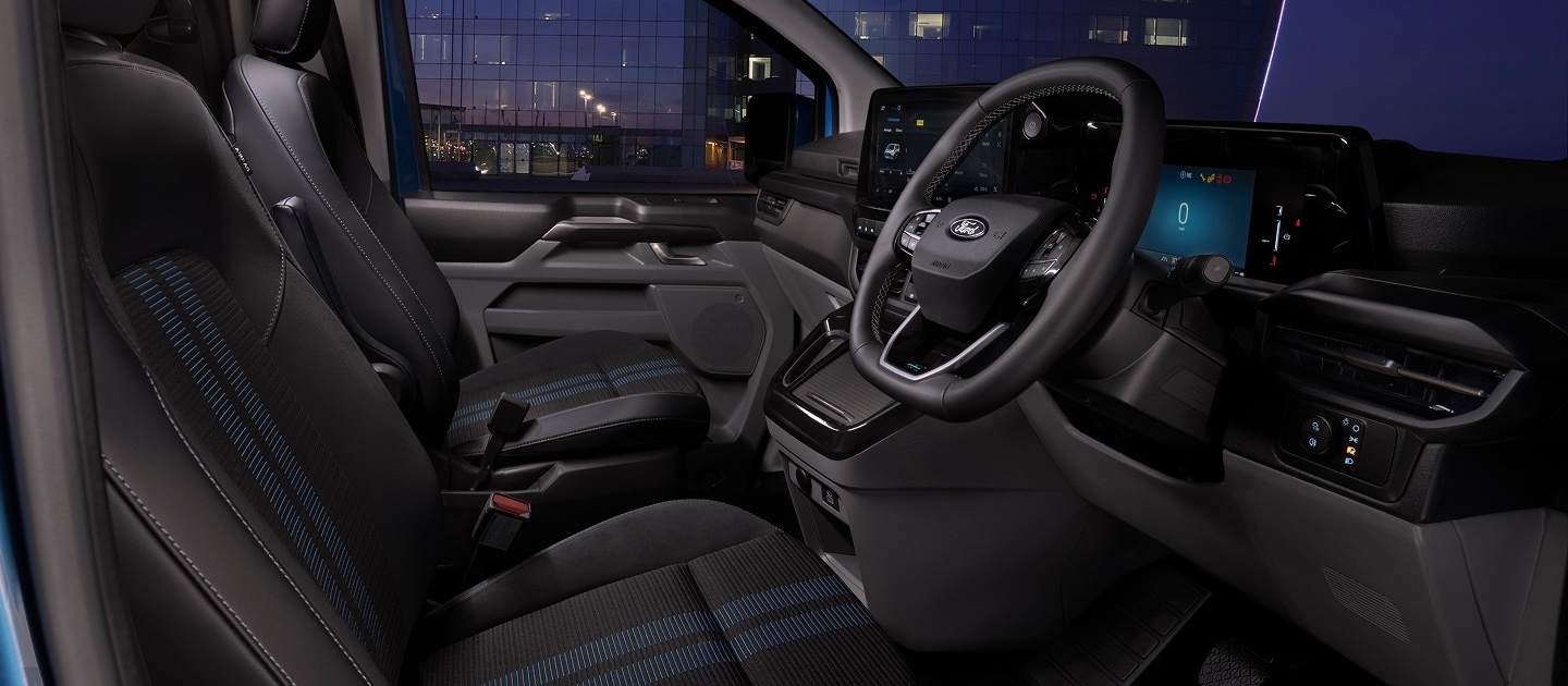The inside of a Ford E-Transit Custom electric van, showing the steering wheel and infotainment screen.