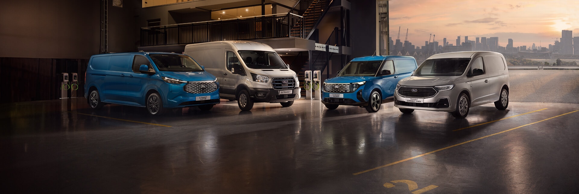 The range of Ford electric and plug-in hybrid vans parked inside a garage. 