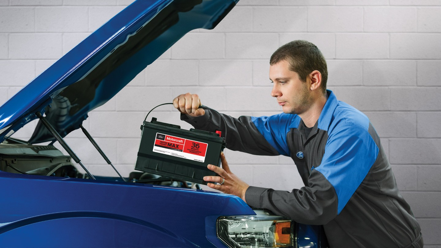 A service worker replaces the battery in the car
