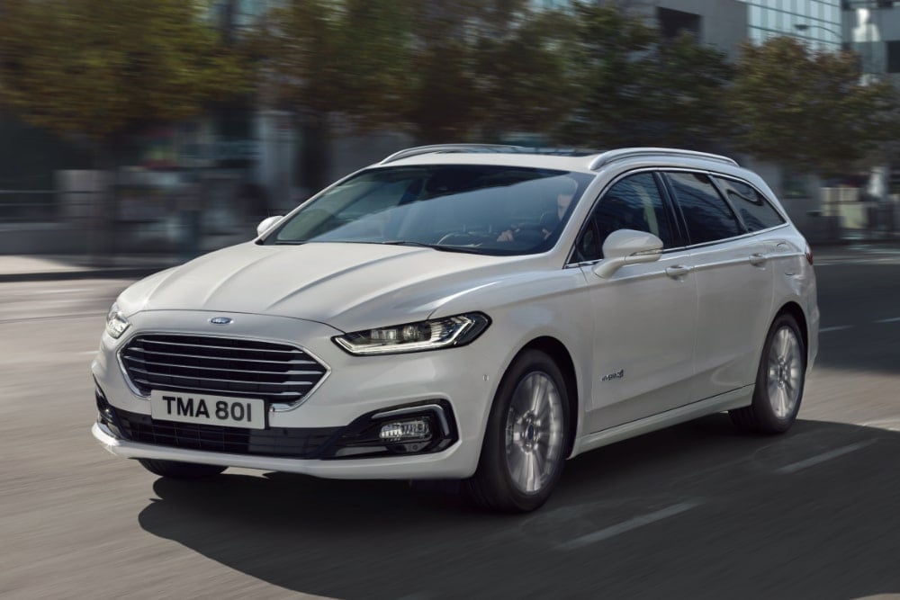 A white Ford Mondeo estate car driving on a city road.