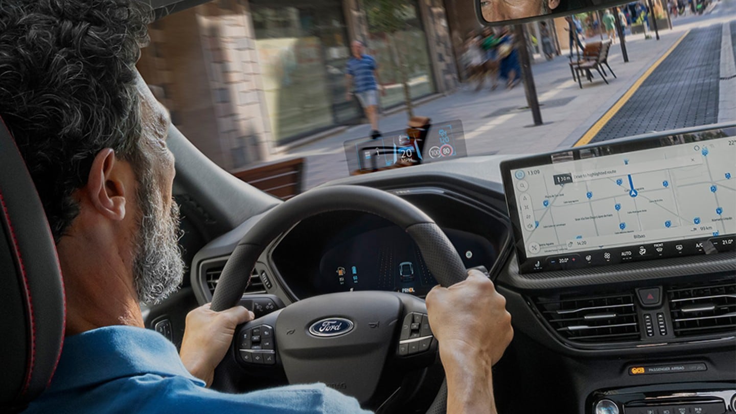 An interior photo of a man driving the Ford Kuga along a city road. 