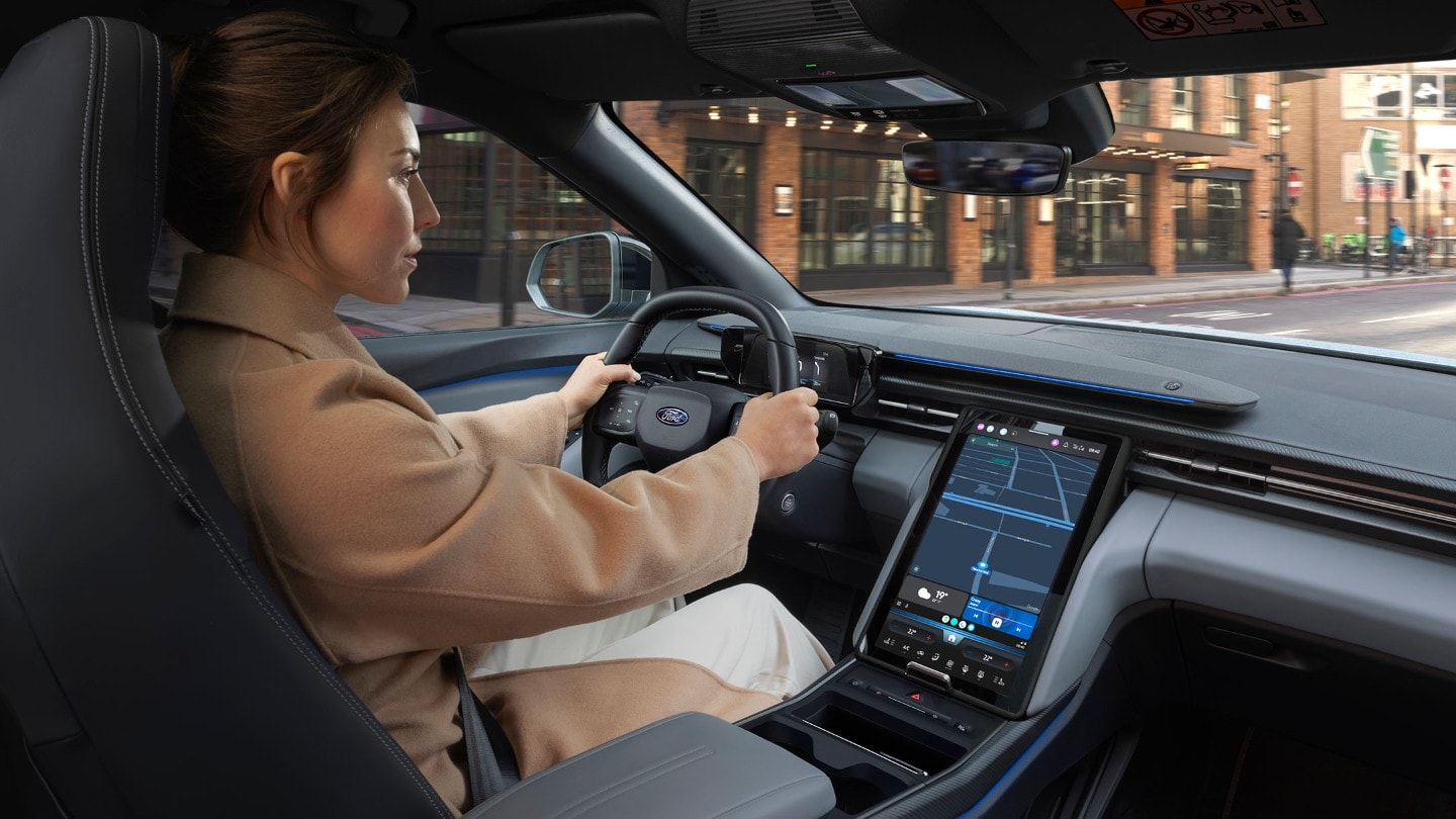 An interior photo of a woman driving the Ford Explorer along a city road. 