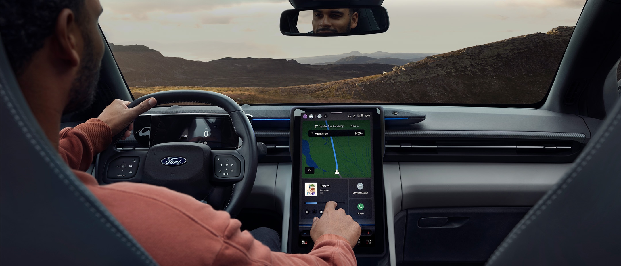 A man sitting in the driving seat of the Ford Explorer, interacting with the large SYNC touchscreen.