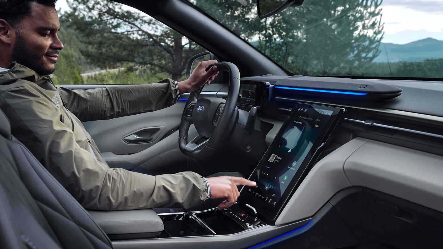 A man sitting in the driving seat of the Ford Explorer, interacting with the large SYNC touchscreen.