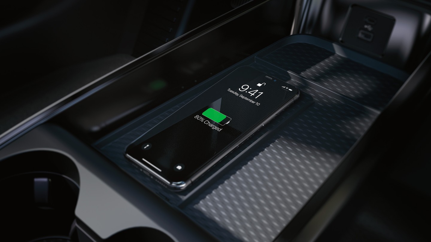 A close up of the wireless charging pad in the centre console, showing an iPhone being charged.