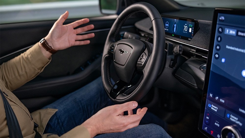 A man sitting in the Ford Mustang Mach-E with his hands away from the steering wheel, showing the BlueCruise technology.