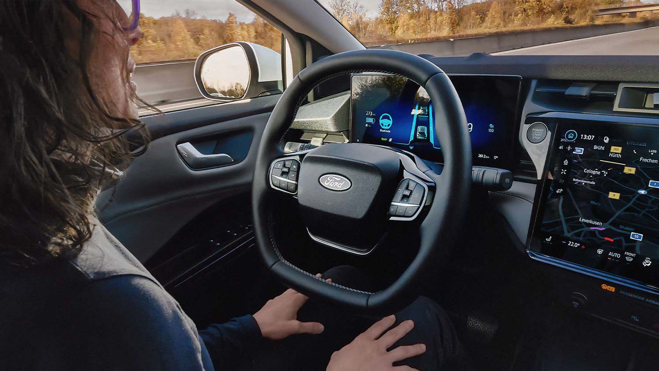 A man sitting in the Ford Mustang Mach-E with his hands away from the steering wheel, showing the BlueCruise technology.