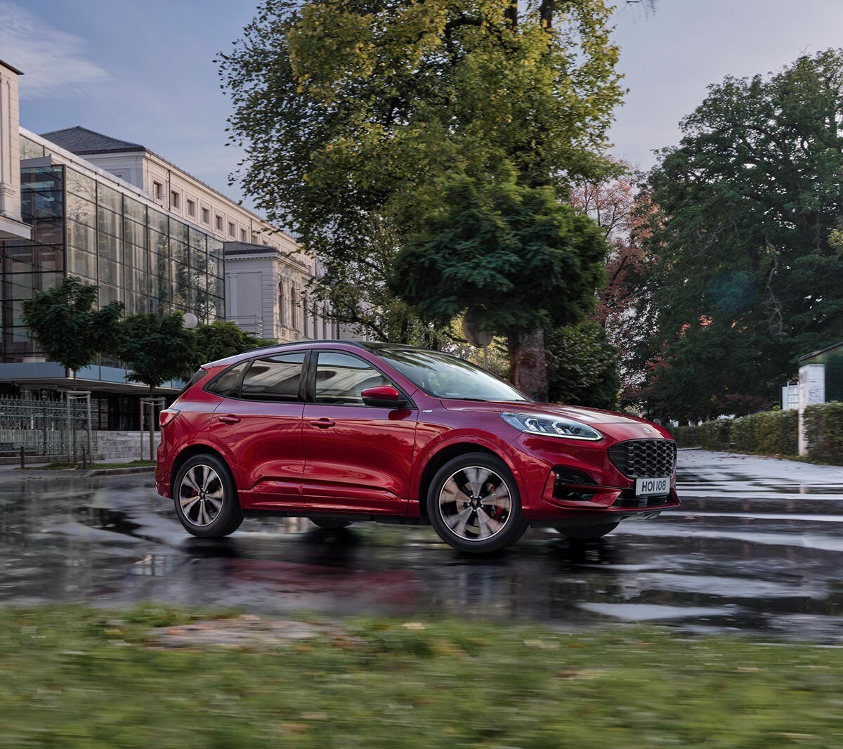 All New red Ford Kuga sideview driving on road