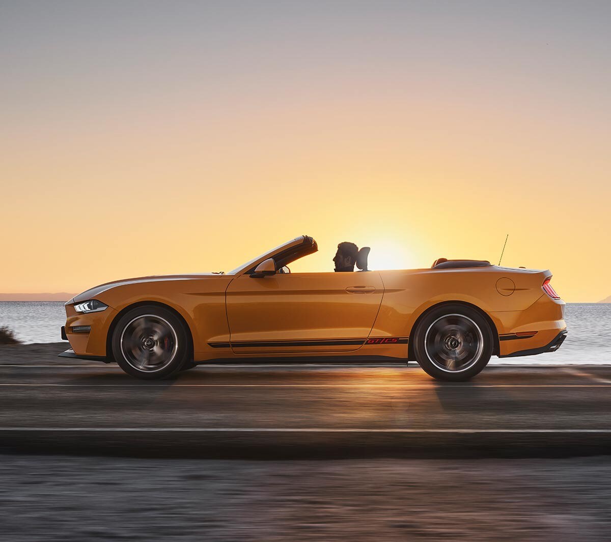 Ford Mustang California Edition driving on a highway against a sunset backdrop