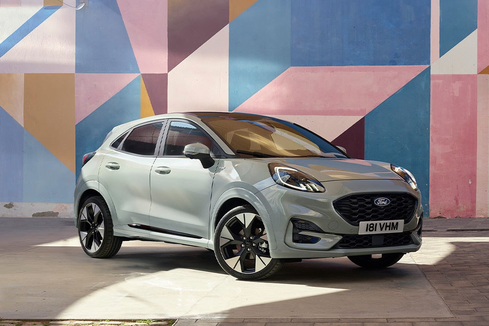 A silver Ford Puma SUV parked in front of a colourful geometric mural.