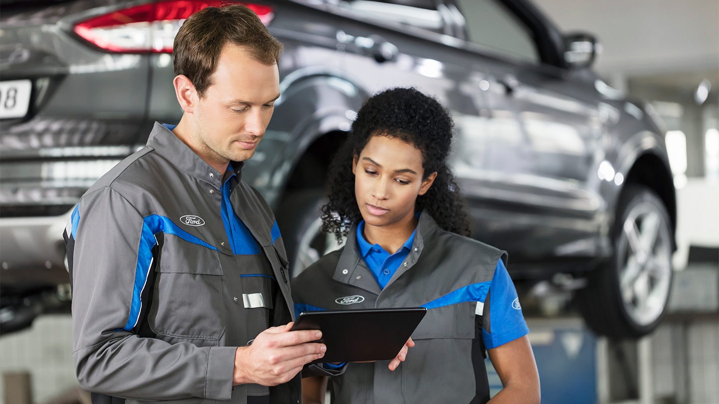 Two Ford repairs specialists check their online service booking system on a phone
