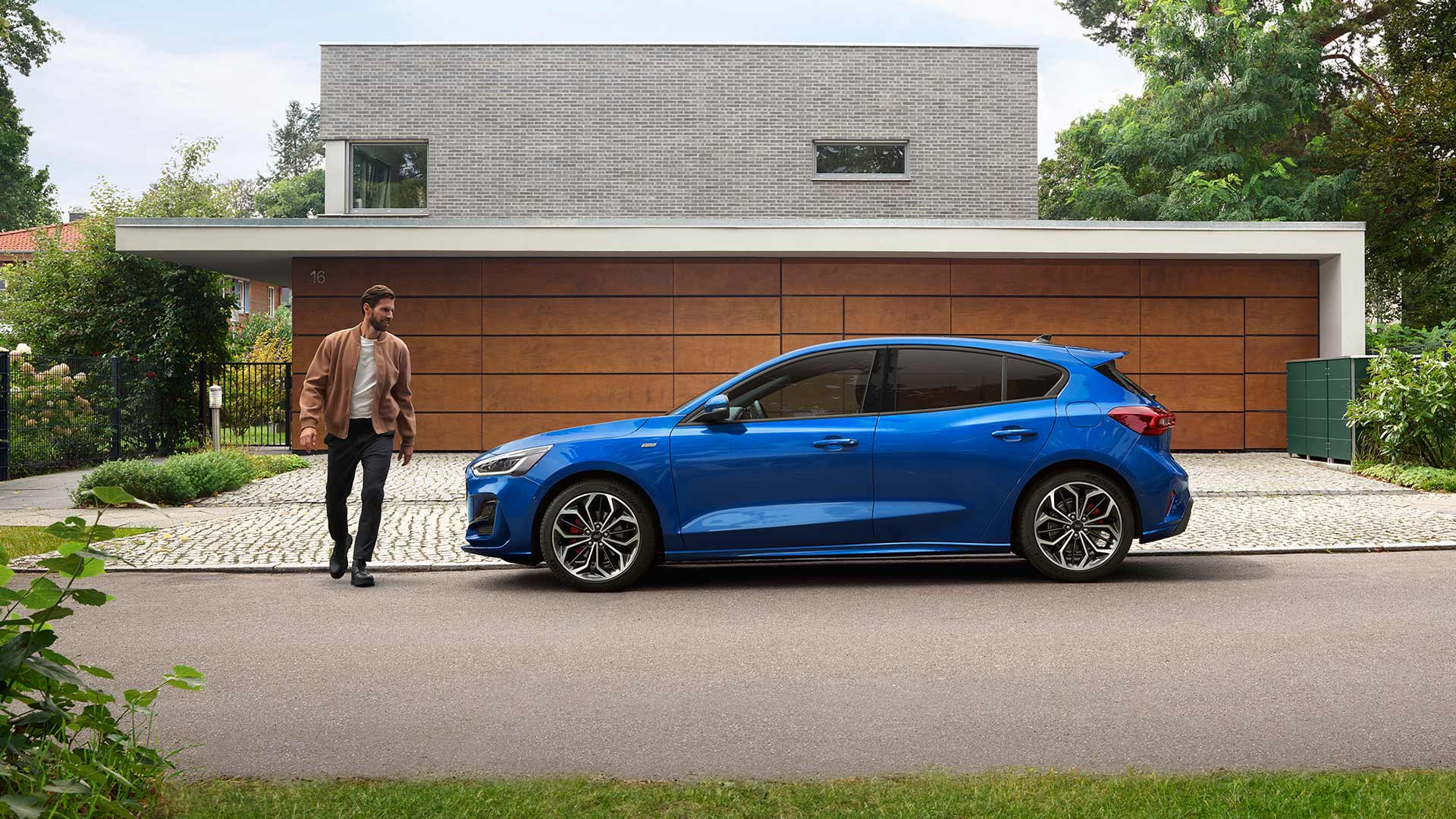 Man approaching a blue Ford Focus parked outside a house