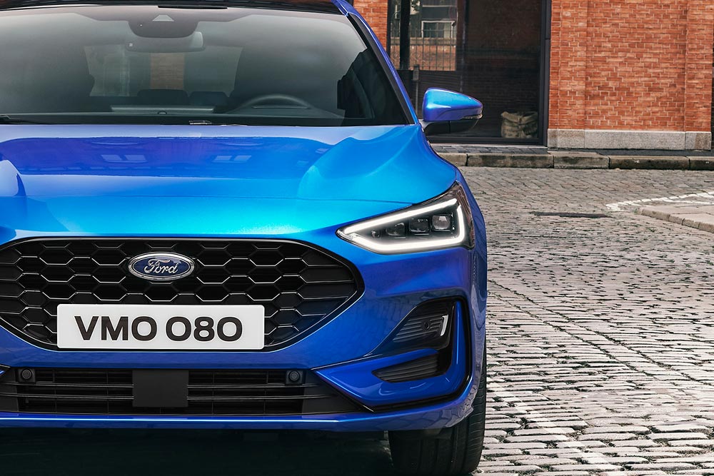 Front view of a blue Ford Focus, highlighting the headlights and grille.