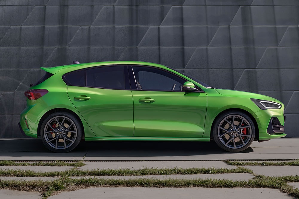 The side of a Mean Green Ford Focus ST hatchback parked off road.