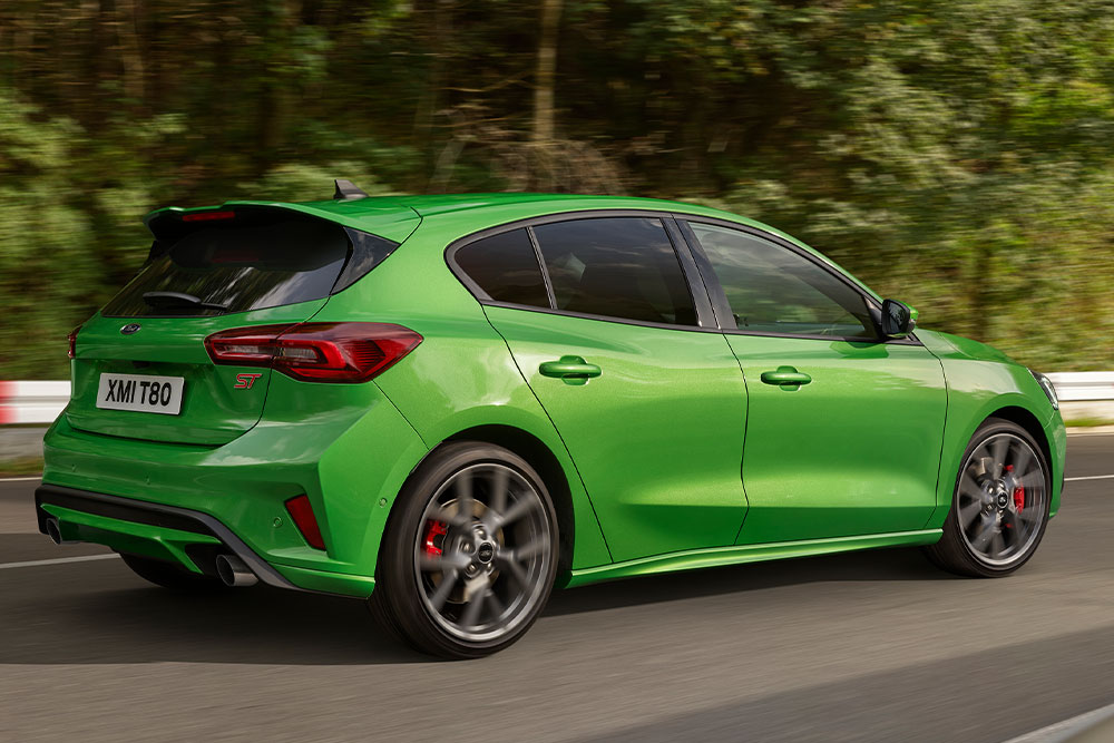 Rear view of a Mean Green Ford Focus ST hatchback driving on a racetrack.