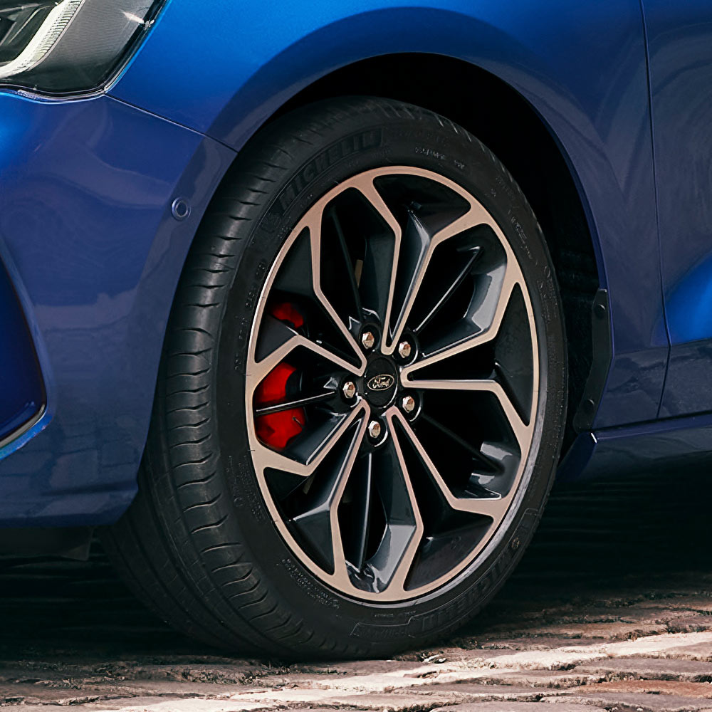 Close-up of the grey alloy wheels with red brake calipers on a blue Ford Focus.