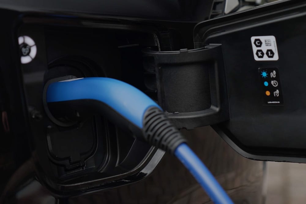Close-up of a blue charging cable plugged into an electric vehicle charging port.