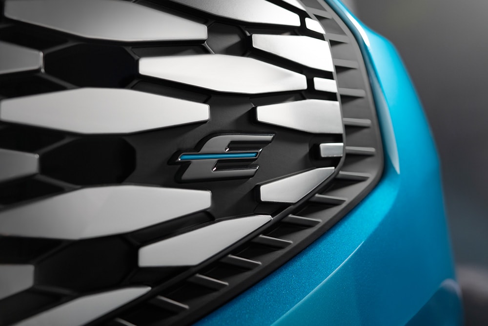 Close-up of the Ford E-Tourneo Custom's grille, featuring the blue "E" logo exclusive for Ford electric vehicles.