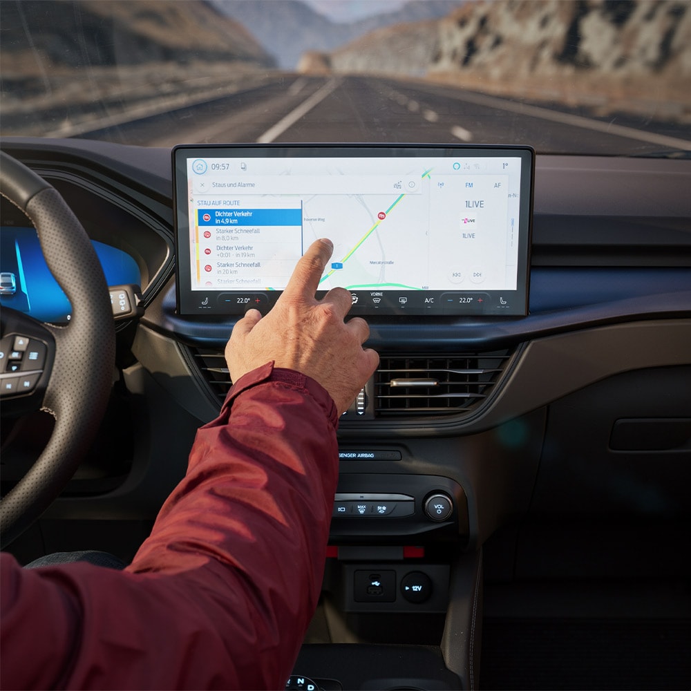 A driver using the Connected Navigation feature on the digital screen in a Ford Kuga BlueCruise Edition.