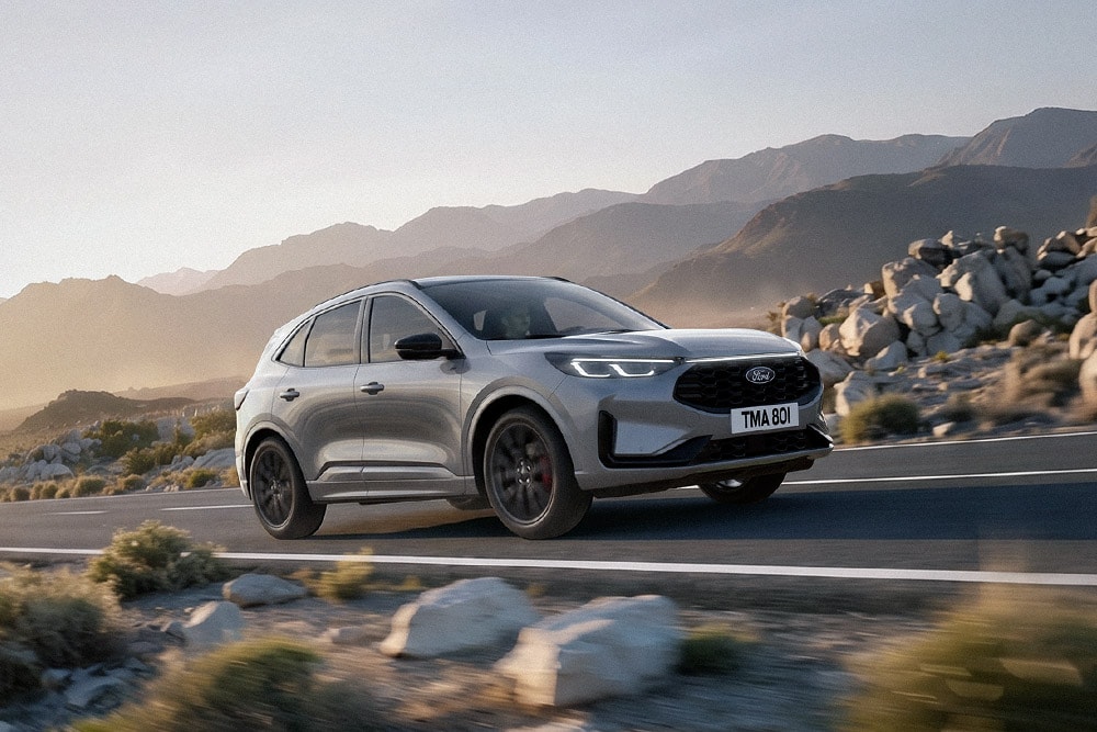 Silver Ford Kuga through a rocky mountainous landscape.
