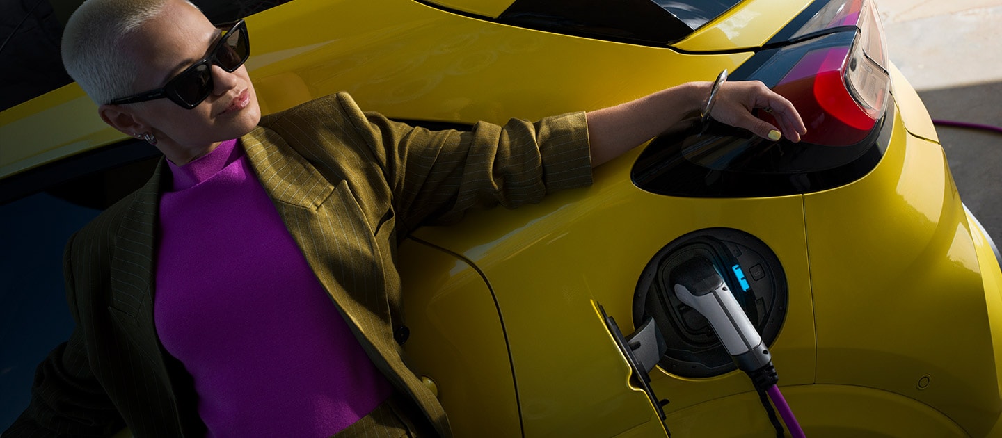 A close up on the rear of a yellow electric Ford Puma Gen-E®, plugged in to a home wallbox.