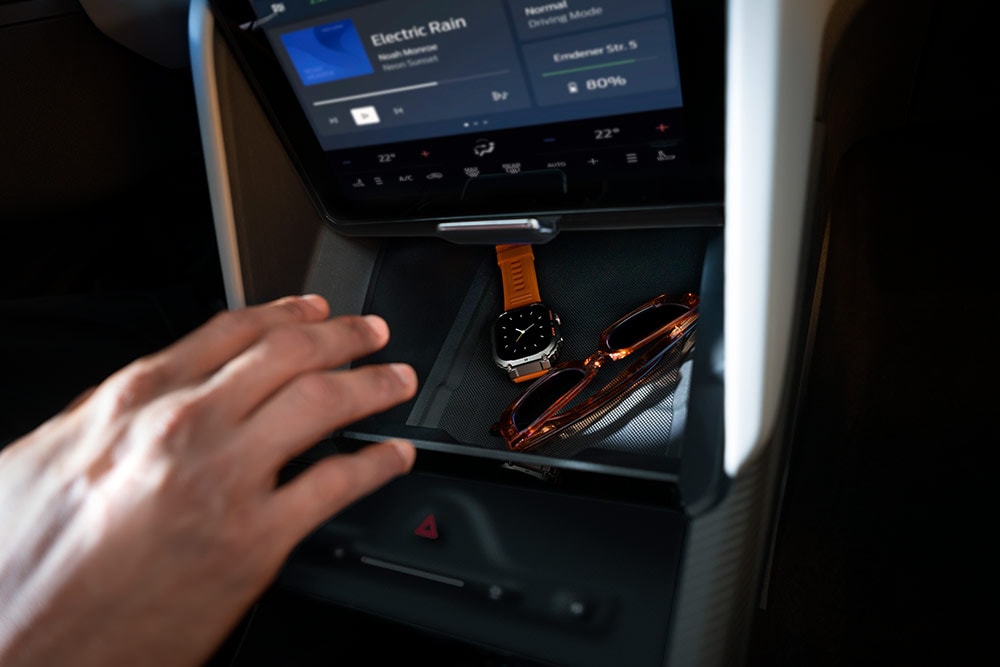 A hand reaches toward the open My Private Locker compartment in the Ford Capri®, revealing a watch and a pair of sunglasses inside.