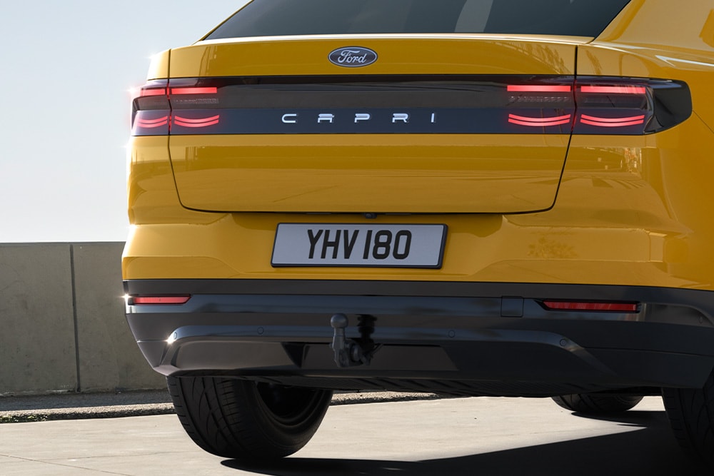 Rear view of a yellow Ford Capri® driving on an urban road.