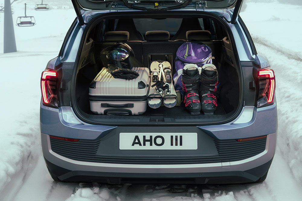The rear luggage space of the Ford Explorer filled with a white suitcase and ski equipment placed through the luggage hatch.