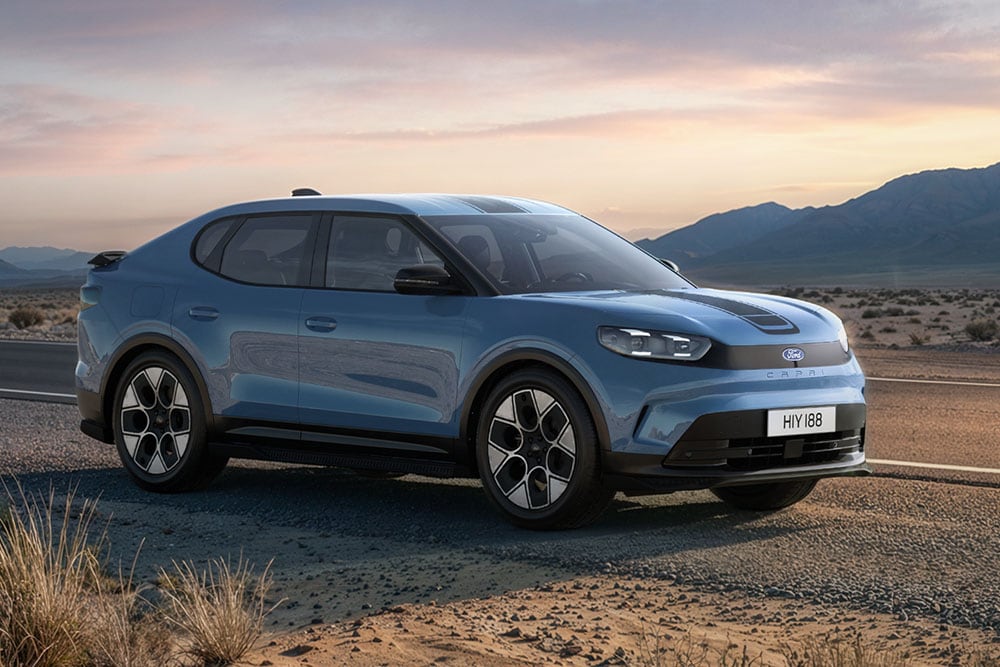 Blue Ford Capri Collection parked along a rugged mountainous road at dusk.