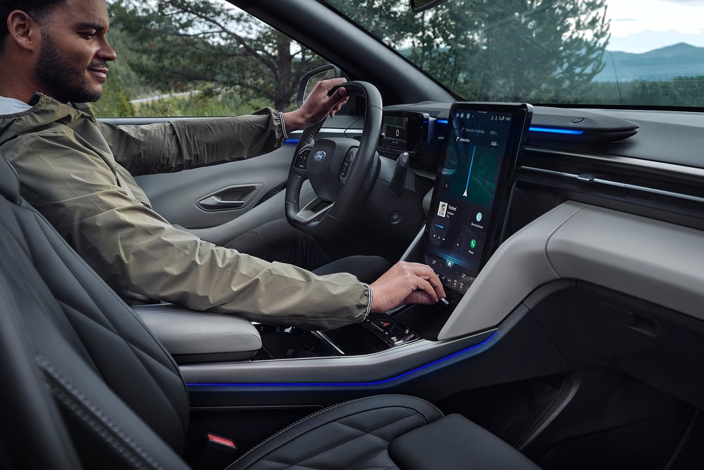 Driver using the touchscreen infotainment system inside the Ford Explorer family SUV.