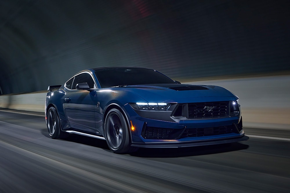 A vapour blue Ford Mustang sportscar driving through a tunnel.