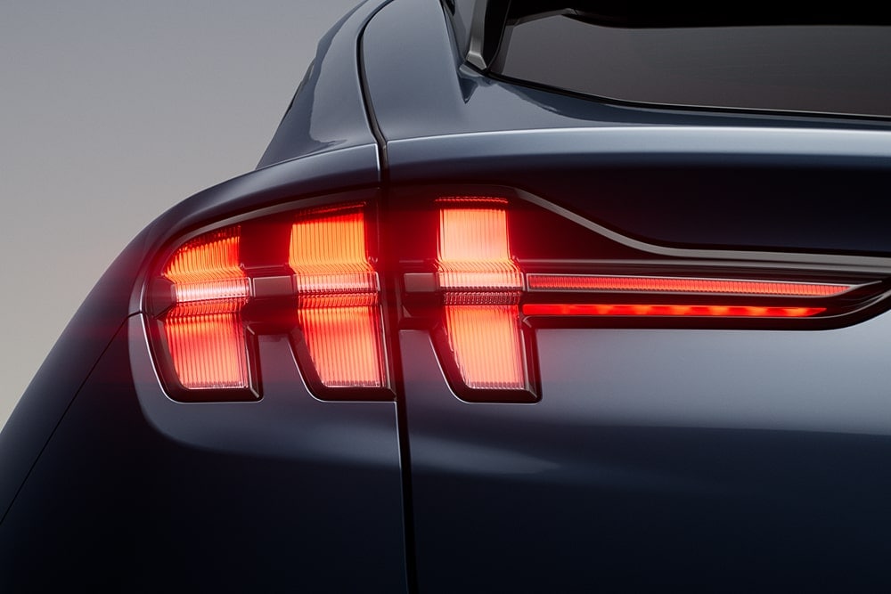 Close-up of illuminated triple tail lights on a Ford Mustang Mach-E sports car.