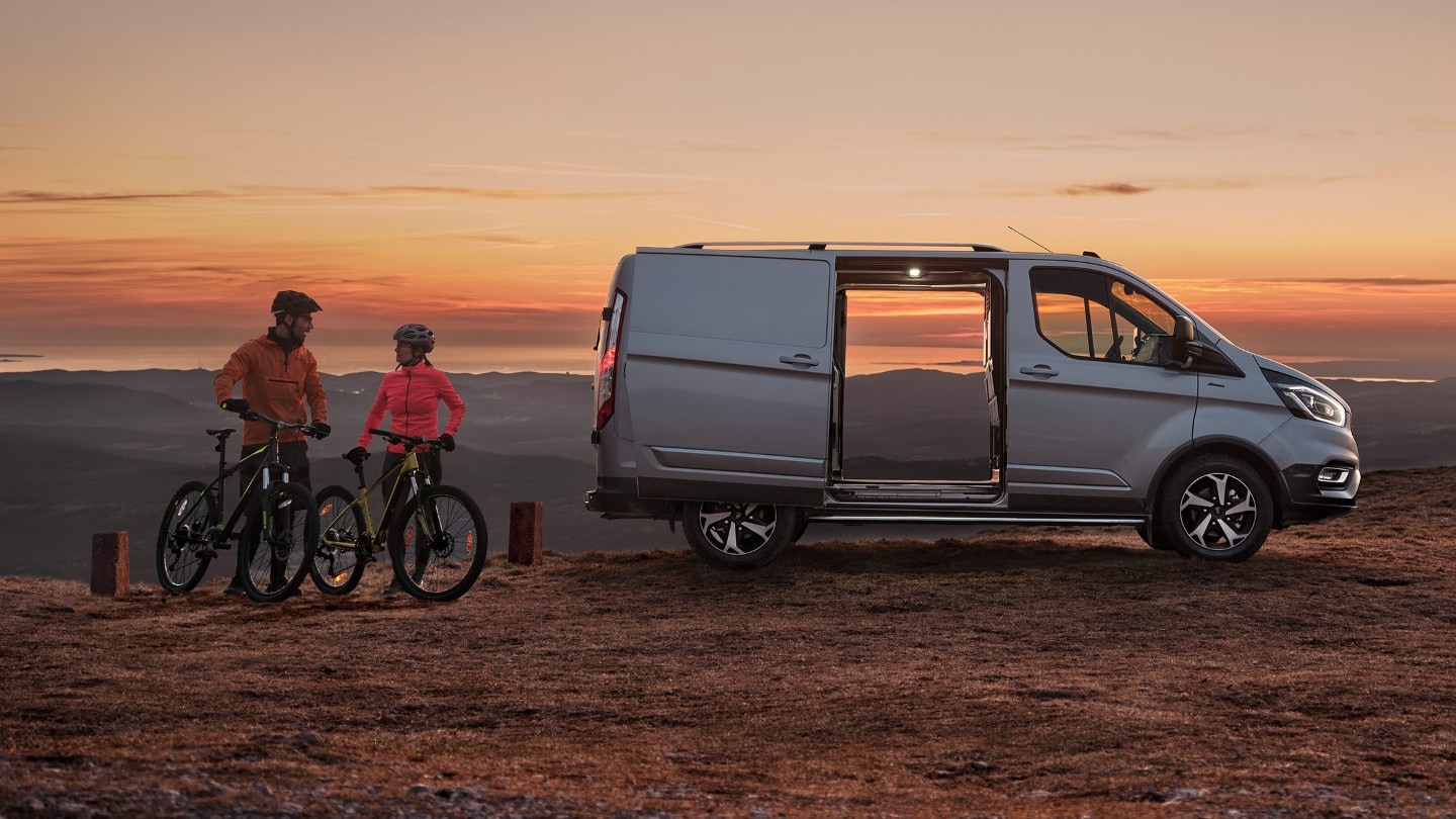 Ford Transit Custom Active side view with open door against sunset and two cyclists