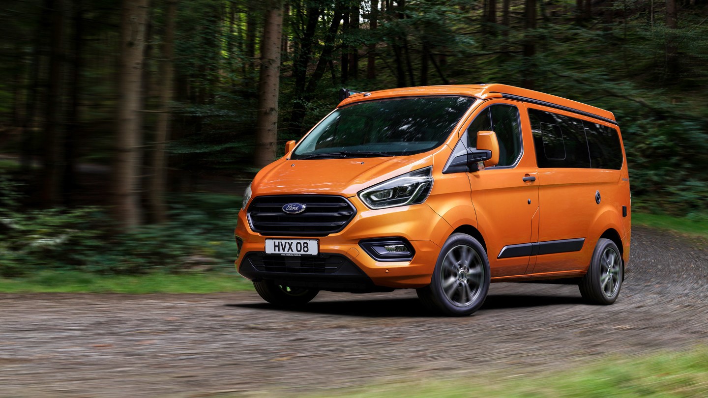 Orange Ford Transit Custom Nugget driving in forest