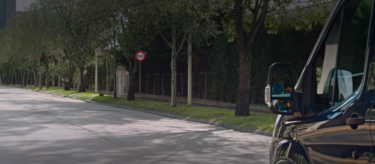 Side view of a Ford Transit Minibus on a tree-lined street.