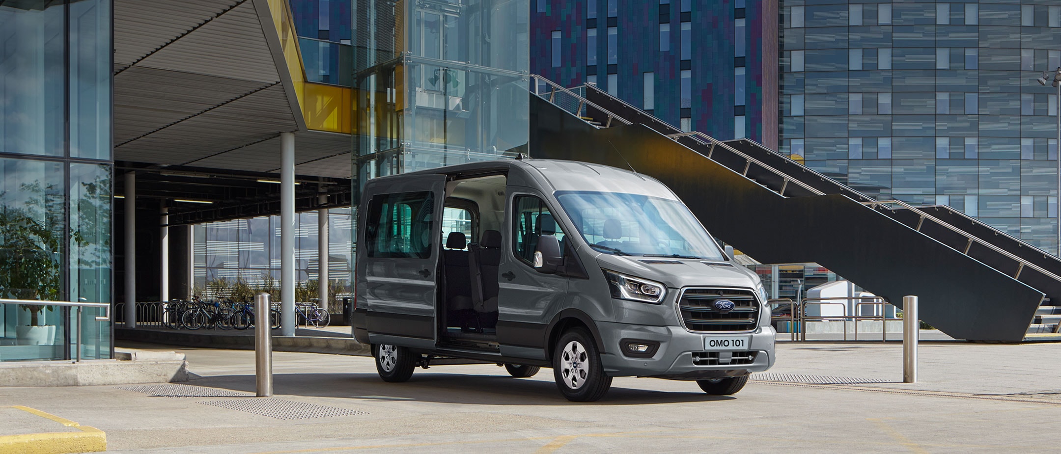 Ford Transit Minibus parked in front of a modern building with the side door open