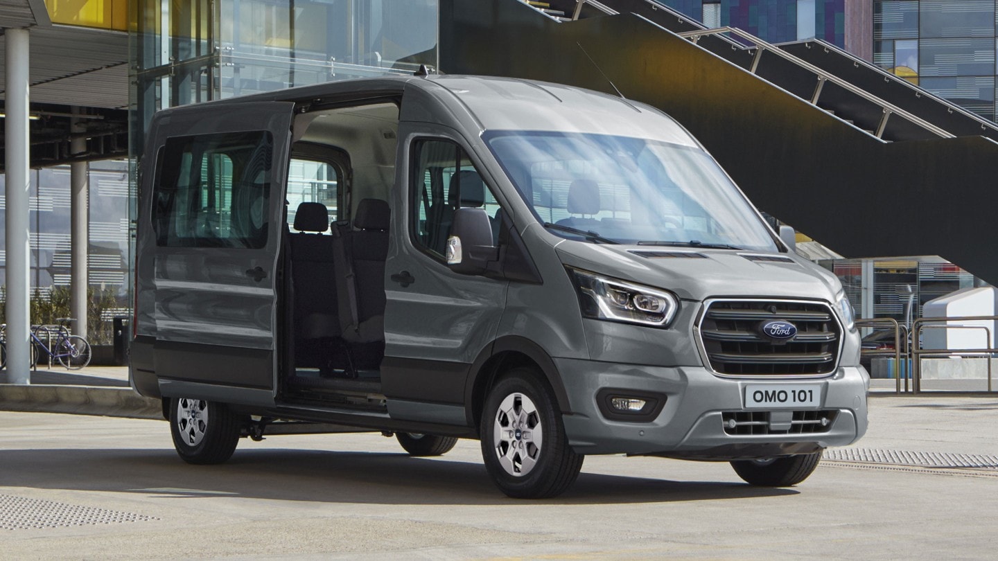 Ford Transit Minibus parked in front of a modern building with side door open