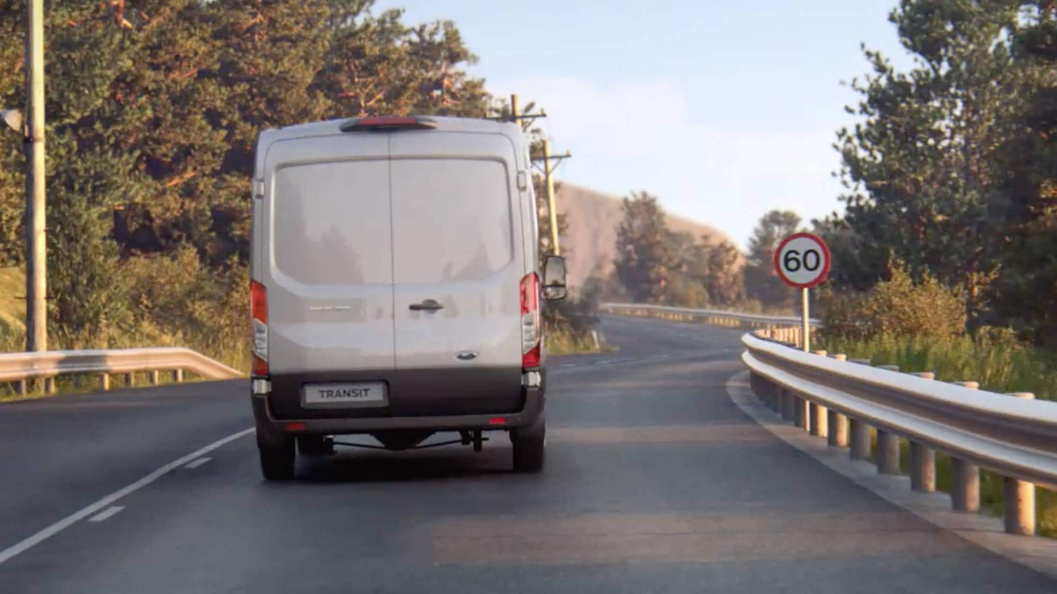 Ford Transit Van driving on the road with traffic sign viewed from back