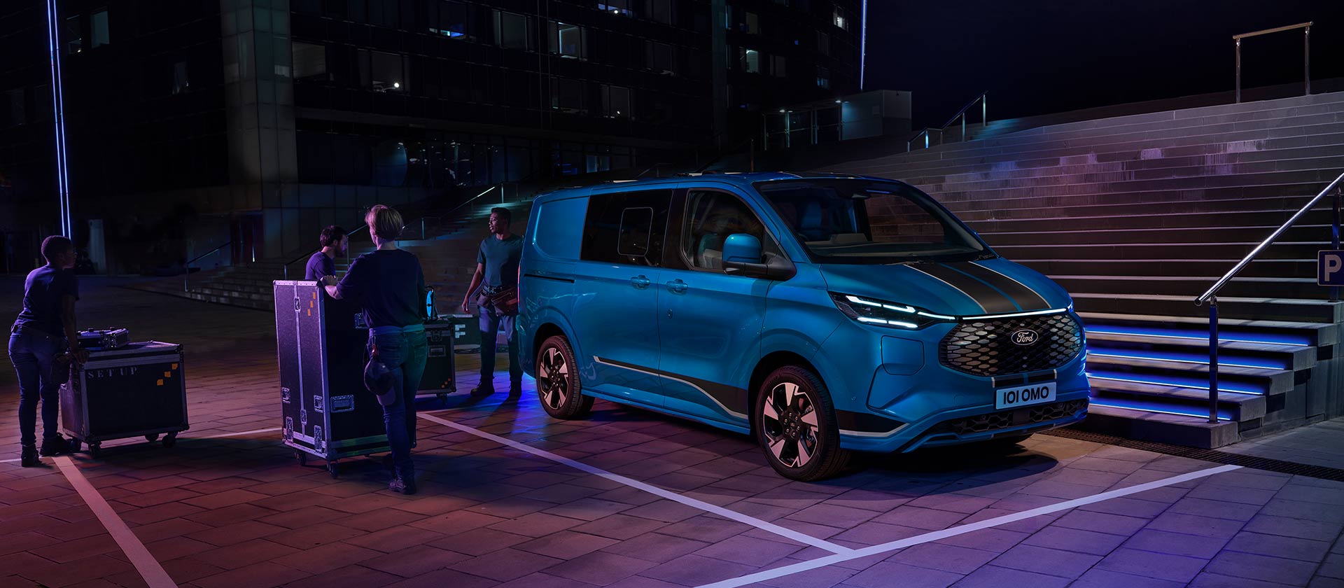 Blue Ford E-Transit Custom electric van being loaded at night. 