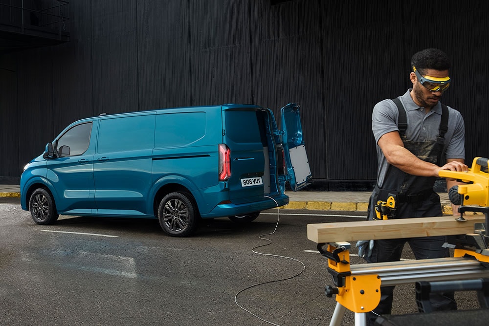 Blue Ford Transit Custom van and a person using power tools.