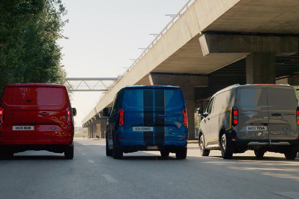Three Ford Transit Custom vans driving on a highway.