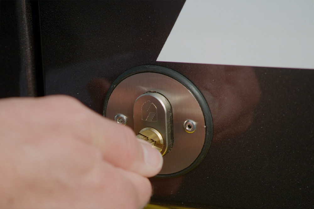 Hand locking a van door with a key.