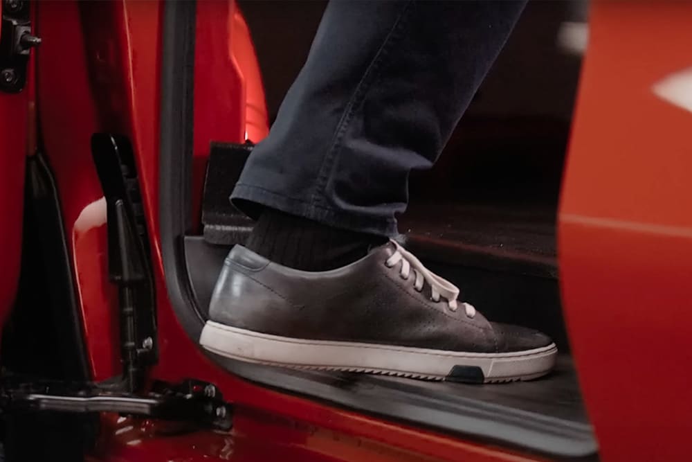 Foot stepping into a red Ford Transit Custom.